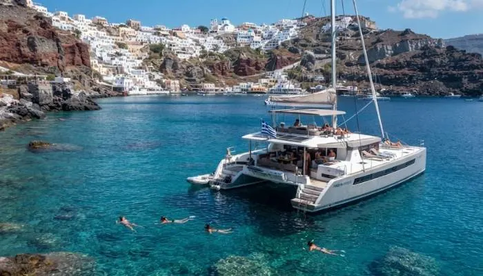 Spacious catamaran anchored in a clear blue swimming bay in Santorini