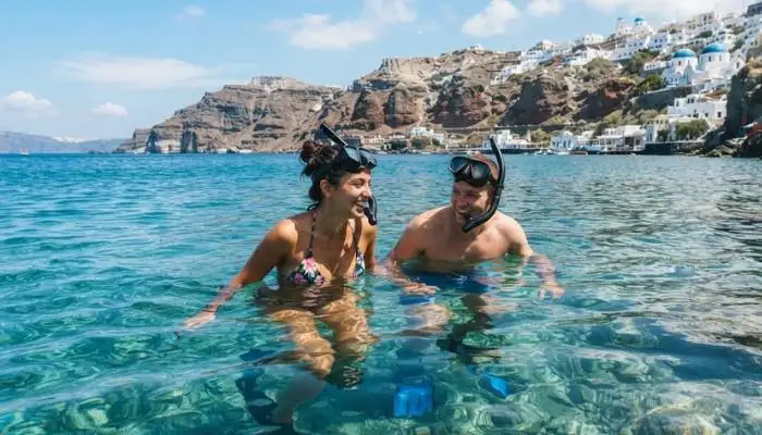 Couple swimming and snorkeling in the crystal-clear waters of Santorini